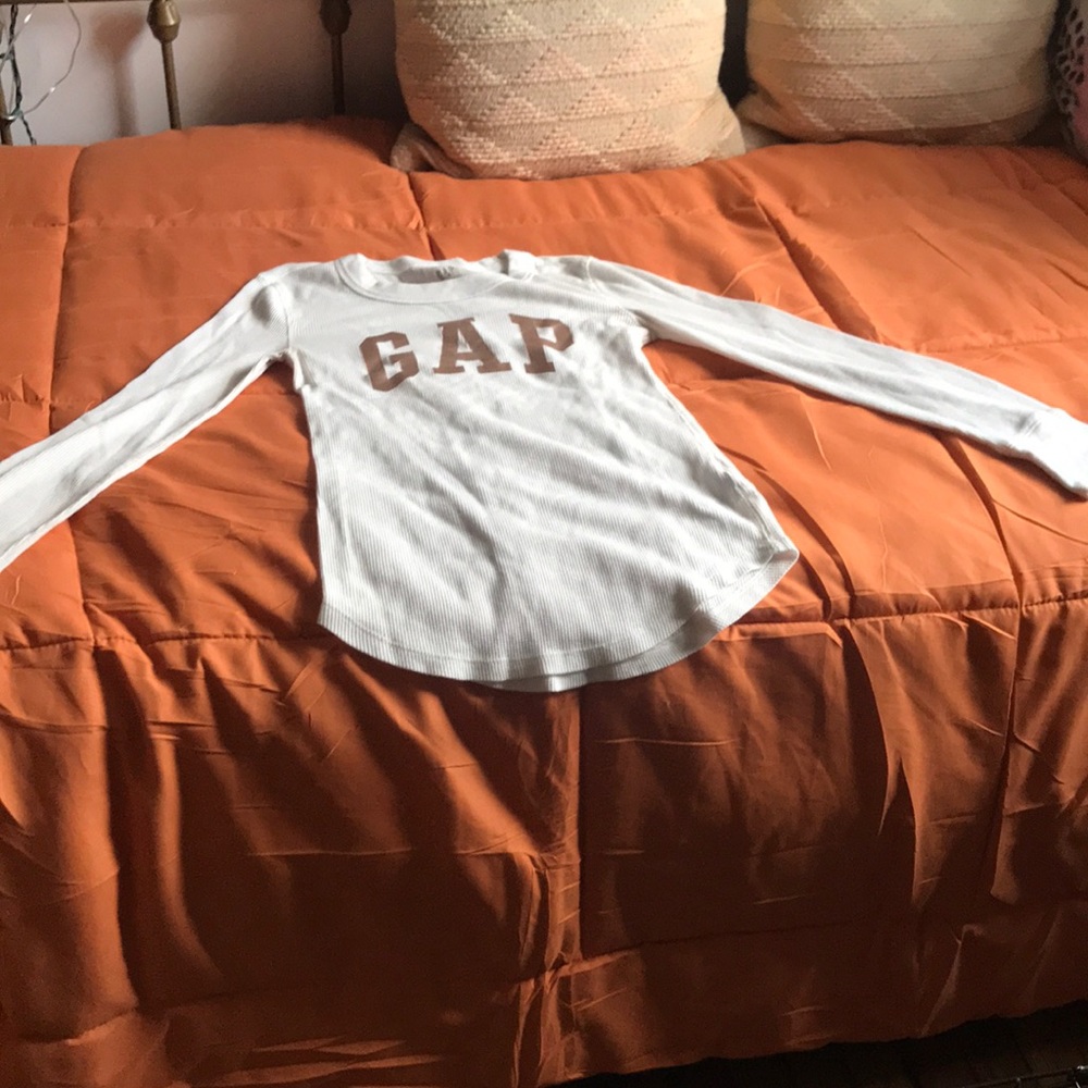 A white knit styled long sleeve, gold lettering GAP shirt in a size XS